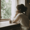 窓辺で自分の気持ちと向き合いながら静かに考える女性