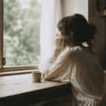 窓辺で自分の気持ちと向き合いながら静かに考える女性