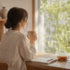 朝の光が差し込む部屋で、お茶を飲みながら静かに自分と向き合う女性